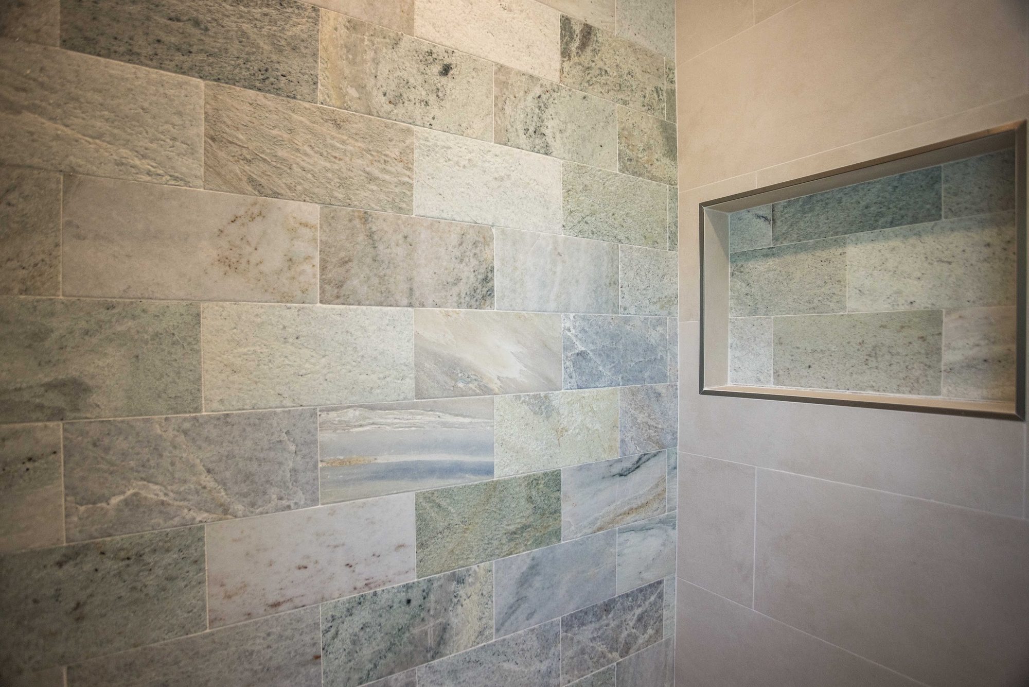 Natural stone tile shower niche finished in a second-story primary suite bathroom